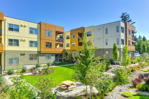 Community Open Green Spaces, with picnic bench and table with walkways around community and  Apartment buildings surrounding the courtyard area.